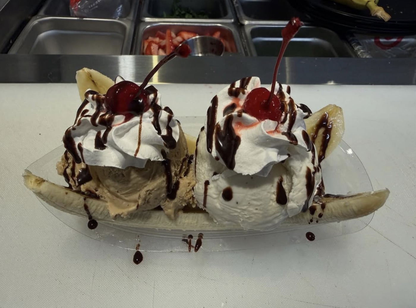 Banana split with two ice cream scoops, whipped cream and cherries