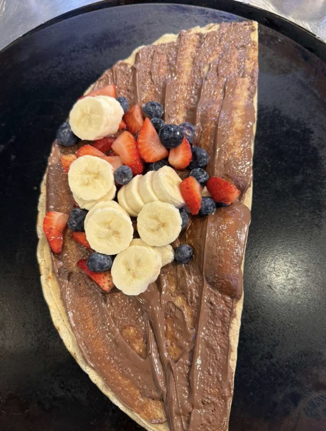 Nutella crepe topped with banana, strawberry and blueberries