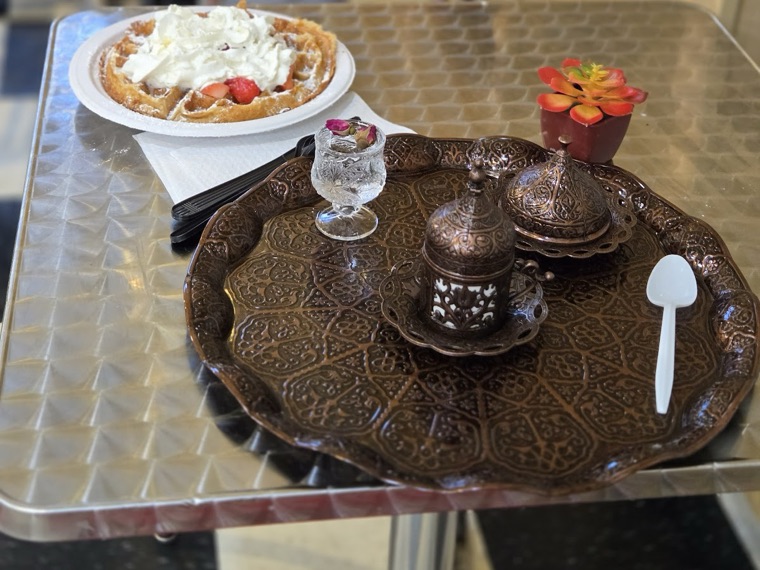 Photo from Somjai Deginda's Google review — waffle with whipped cream and strawberries beside a Turkish coffee set